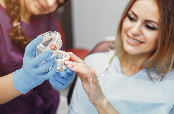 diş hekimi elindeki diş protezi sürecini hastaya anlatıyor
