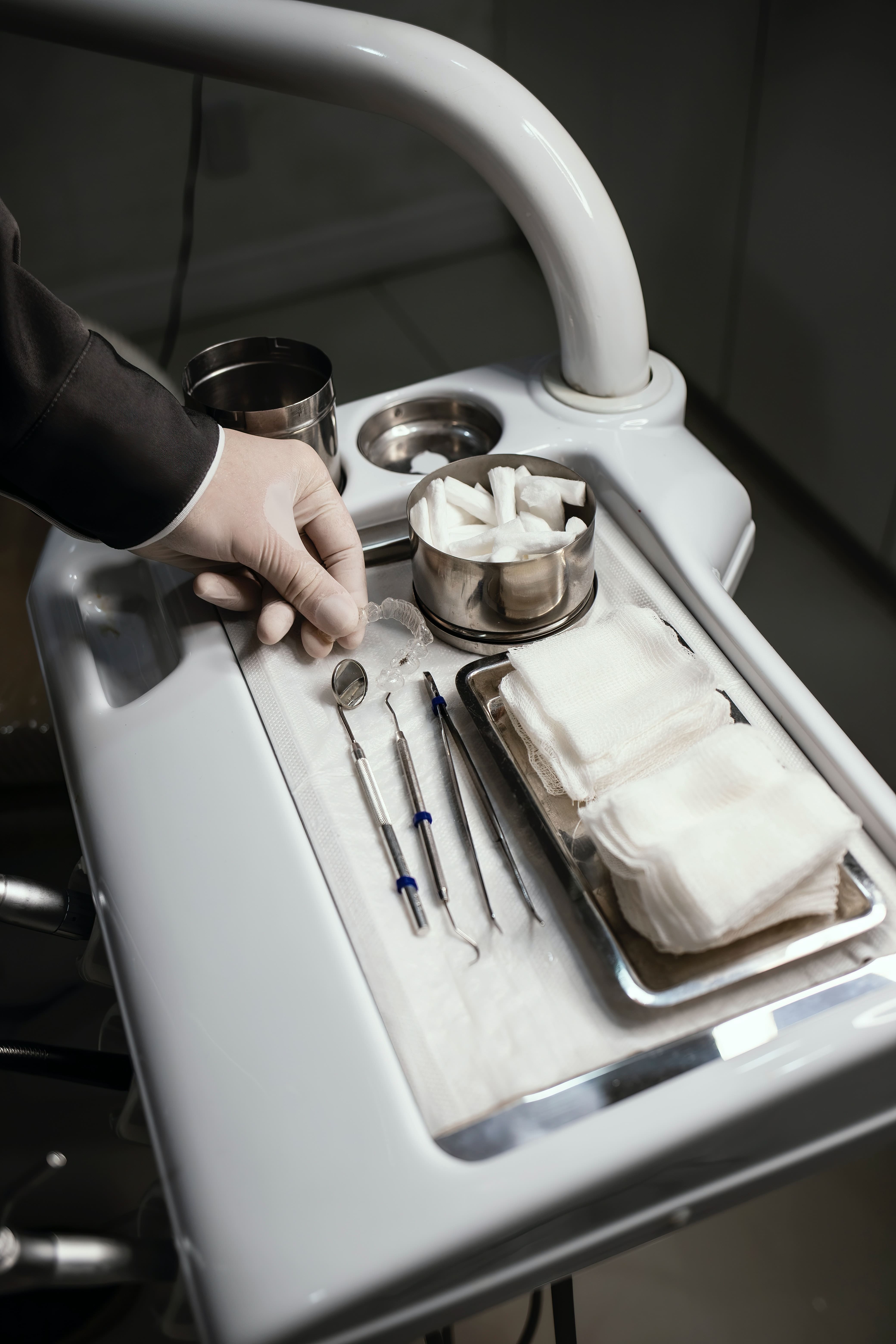 diş doktoru elinde şeffaf plak tutuyor ve masada diş aletleri bulunuyor