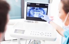 Diş hekimi, hastasına dental analiz yazılımı ile radyografi gösteriyor