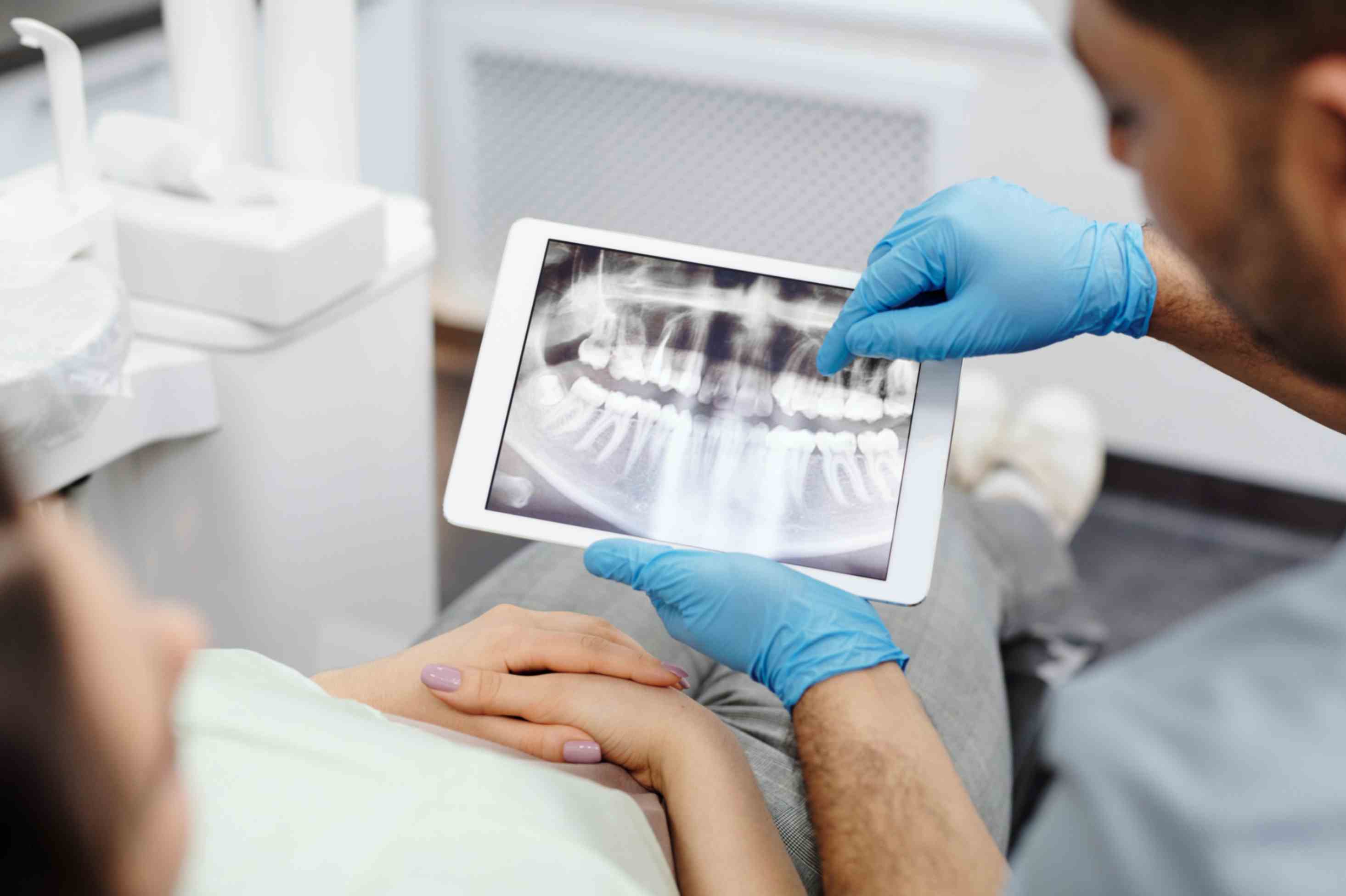 dentist shows patient's dental x-rays and problems on tablet