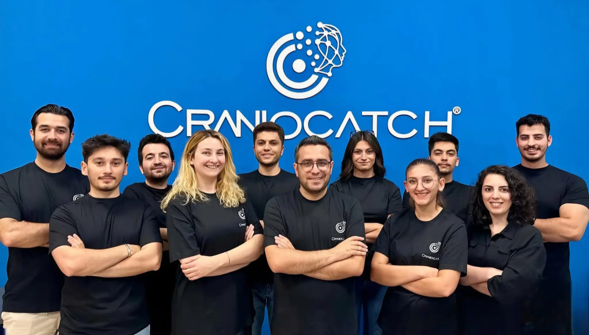 Dizüstü bilgisayarlarla bir masa etrafında birlikte çalışan CranioCatch ekibi